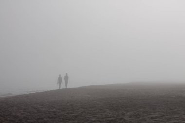 Plaj sisli ve tanınmayan insanlarla dolu.