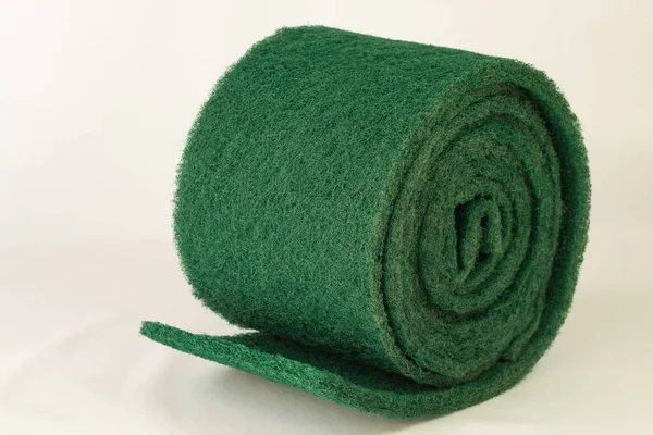 Scourer with its typical green color on a roll to clean the dishes