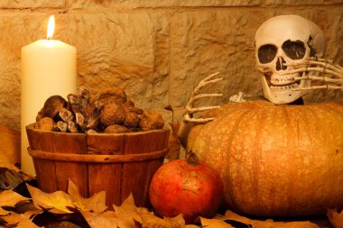 Cadılar Bayramı sonbahar kompozisyonu balkabağı, kafatası, kurutulmuş meyve, mango, sepette fındık ve mum