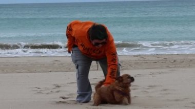 San Juan Sahili, Alicante, İspanya 'da köpek Nami ile oynayan genç bir kadın.