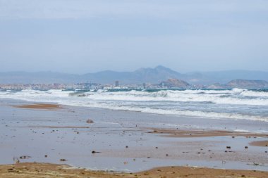 Alicante körfezi üzerinde güçlü rüzgarlı bir gün. Arka planda şehir ve İspanya 'nın El Altet plajından güçlü dalgalar var.