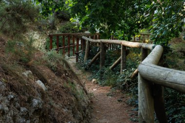 Alcoy, İspanya 'daki Preventorio eğlence alanındaki ahşap korkuluk ile köprüye erişim yolu