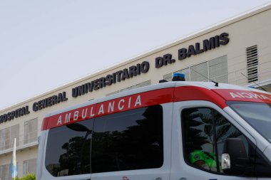 Alicante, İspanya, 07-18-2024: Genel Üniversite Hastanesinin cephesi Dr. Balmis (İspanya) geçerken bir ambulans geçiyor