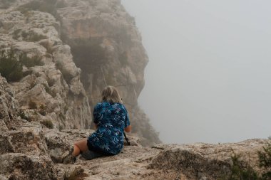 Fotoğrafçı, Sierra de Mariola doğal parkında, Alcoy, İspanya 'da bulutlar ve sis ile manzaranın fotoğraflarını çekerken yatıyordu.