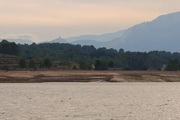 Arkasında Sierra de Mariola doğal parkı olan Beniarres rezervuarının üzerinde günbatımı olan manzara, İspanya