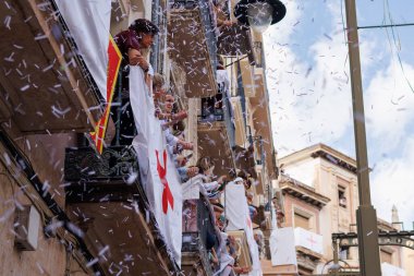 Alcoy, İspanya, 05-03-2025: Alcoy 2025 Moors ve Hristiyan geçit töreni sırasında süslü balkonlarda konfeti atan ve alkışlayan insanlar