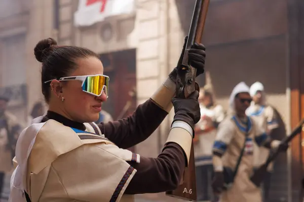 Alcoy, İspanya, 05-05-2025: Alcoy 2025 'teki Moors ve Hristiyan festivali sırasında bir arquebus ateşlemeden önce gözlerini koruyan kadın.