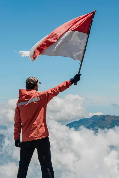 Azjatycki Mężczyzna Indonezyjską Flagą Indonezji Szczycie Góry Pod Błękitnym Niebem — Zdjęcie stockowe