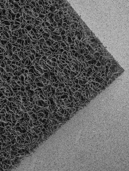 The textured background of a floor mat consists of many curly nylon threads that overlap each other. And a place to clean your feet when you enter the house