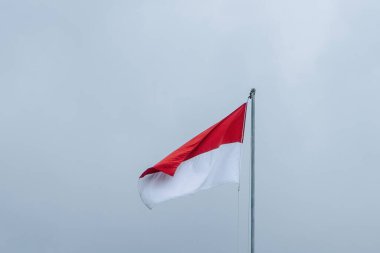 Bu resim Endonezya 'nın görkemli bayrağı Merah Putih' i yakalıyor, en uzun bayrak direğinin üzerinde gururla dalgalanırken, dramatik bir bulutlu arka plan üzerine kurulmuş.