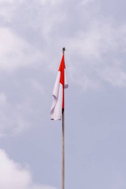 Görkemli bir Endonezya bayrağı, dramatik ve bulutlu bir gökyüzüne gururla el sallıyor. En uzun direğe asılan bayrak, ulusun ruhunu ve direncini simgeliyor..