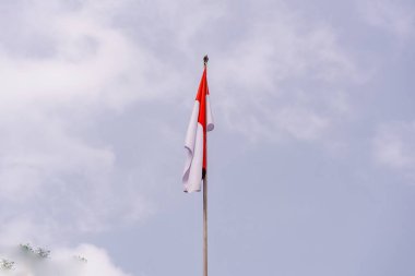 Görkemli bir Endonezya bayrağı, dramatik ve bulutlu bir gökyüzüne gururla el sallıyor. En uzun direğe asılan bayrak, ulusun ruhunu ve direncini simgeliyor..