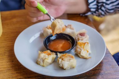 Bir tabak Dim Sum 'un yakın plan fotoğrafı. Zarif ambalajları ve dumanı tüten sıcak dolguyu sergiliyor.