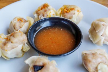 Bir tabak Dim Sum 'un yakın plan fotoğrafı. Zarif ambalajları ve dumanı tüten sıcak dolguyu sergiliyor.