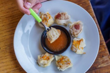 Bir tabak Dim Sum 'un yakın plan fotoğrafı. Zarif ambalajları ve dumanı tüten sıcak dolguyu sergiliyor.