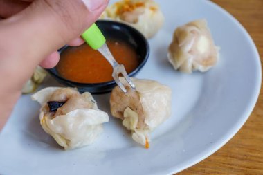 Bir tabak Dim Sum 'un yakın plan fotoğrafı. Zarif ambalajları ve dumanı tüten sıcak dolguyu sergiliyor.