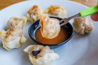 Bir tabak Dim Sum 'un yakın plan fotoğrafı. Zarif ambalajları ve dumanı tüten sıcak dolguyu sergiliyor.