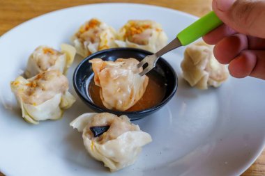 Bir tabak Dim Sum 'un yakın plan fotoğrafı. Zarif ambalajları ve dumanı tüten sıcak dolguyu sergiliyor.