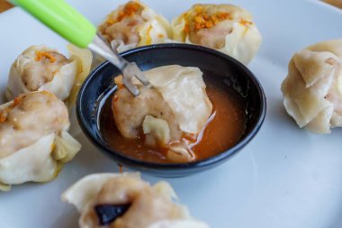 Bir tabak Dim Sum 'un yakın plan fotoğrafı. Zarif ambalajları ve dumanı tüten sıcak dolguyu sergiliyor.