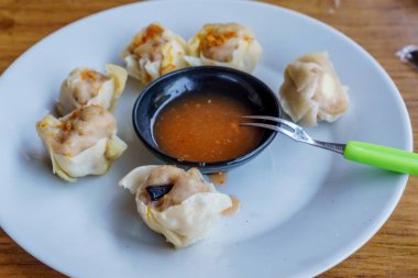 Bir tabak Dim Sum 'un yakın plan fotoğrafı. Zarif ambalajları ve dumanı tüten sıcak dolguyu sergiliyor.