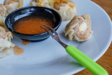 Bir tabak Dim Sum 'un yakın plan fotoğrafı. Zarif ambalajları ve dumanı tüten sıcak dolguyu sergiliyor.