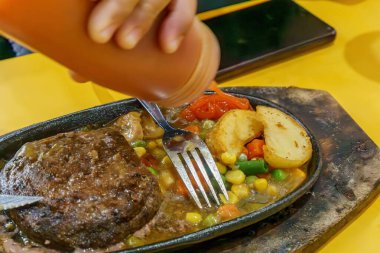 Zengin, baharatlı bir sosun, mükemmel pişirilmiş bir bifteğin üzerine döküldüğü anı yakalayan büyüleyici bir görüntü..