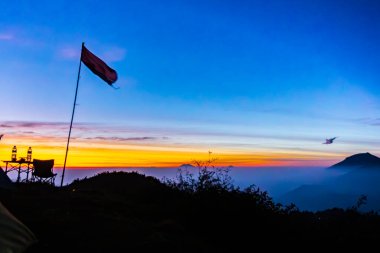 Endonezya bayrağının güçlü bir silueti, Merah Putih, nefes kesici bir altın saat gündoğumuna karşı yakalandı. Ulusal kutlamalar, seyahat ve ilham verici temalar için ideal.