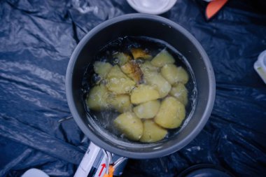 Açık hava yemeklerinin özünü, bir dağ kampı macerası sırasında taşınabilir bir sobanın üzerinde kaynayan patateslerle yakalayın.