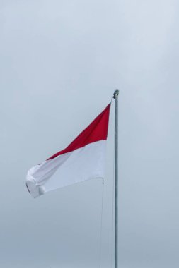Bu resim Endonezya 'nın görkemli bayrağı Merah Putih' i yakalıyor, en uzun bayrak direğinin üzerinde gururla dalgalanırken, dramatik bir bulutlu arka plan üzerine kurulmuş.