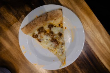 Bu mükemmel dilimlenmiş pizzanın karşı konulmaz cazibesine kapıl. Kırsal bir ahşap masaya karşı beyaz bir tabakta sergileniyor..