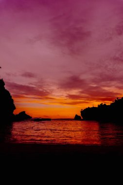 Nglarean Sahili, Yogyakarta 'daki alacakaranlık sihrine tanık olun. Bu nefes kesici fotoğraf güneş batarken gökyüzünü canlı renklerle yakalıyor.