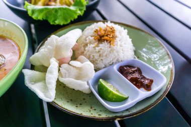 Tüylü pirinç, kızarmış soğan, kraker ve baharatlı sambal ile servis edilen baharatlı Minapadi körili tavuk. Lezzetli ve eksiksiz bir yemek.
