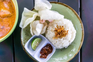 Tüylü pirinç, kızarmış soğan, kraker ve baharatlı sambal ile servis edilen baharatlı Minapadi körili tavuk. Lezzetli ve eksiksiz bir yemek.