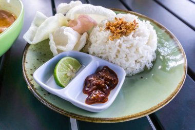 Tüylü pirinç, kızarmış soğan, kraker ve baharatlı sambal ile servis edilen baharatlı Minapadi körili tavuk. Lezzetli ve eksiksiz bir yemek.