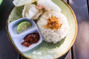 Tüylü pirinç, kızarmış soğan, kraker ve baharatlı sambal ile servis edilen baharatlı Minapadi körili tavuk. Lezzetli ve eksiksiz bir yemek.