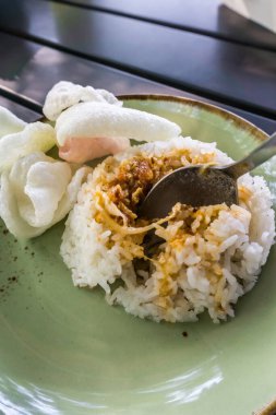 Tüylü pirinç, kızarmış soğan, kraker ve baharatlı sambal ile servis edilen baharatlı Minapadi körili tavuk. Lezzetli ve eksiksiz bir yemek.