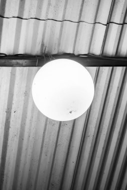 Endüstriyel cazibe ele geçirildi: Yalnız bir ampul çinko çatı ve demir iskeleti aydınlatır, kırsal dokuyu ham, kentsel estetik ile harmanlar.