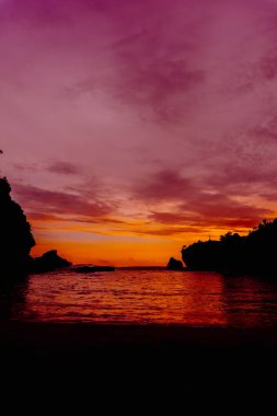 Nglarean Sahili, Yogyakarta 'daki alacakaranlık sihrine tanık olun. Bu nefes kesici fotoğraf güneş batarken gökyüzünü canlı renklerle yakalıyor.