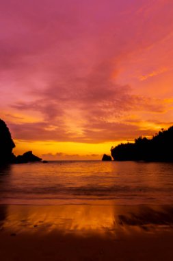 Nglarean Sahili, Yogyakarta 'daki alacakaranlık sihrine tanık olun. Bu nefes kesici fotoğraf güneş batarken gökyüzünü canlı renklerle yakalıyor.
