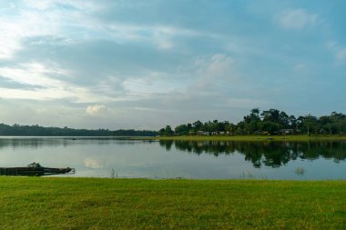 Pofuduk bulutlarla benekli parlak mavi gökyüzünü yansıtan el değmemiş bir gölün dingin güzelliğini yakala..