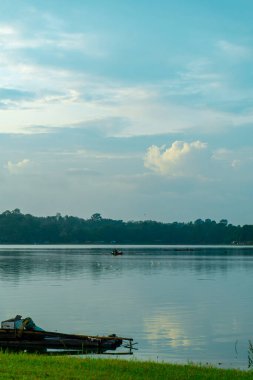 Pofuduk bulutlarla benekli parlak mavi gökyüzünü yansıtan el değmemiş bir gölün dingin güzelliğini yakala..