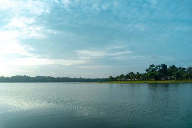 Pofuduk bulutlarla benekli parlak mavi gökyüzünü yansıtan el değmemiş bir gölün dingin güzelliğini yakala..