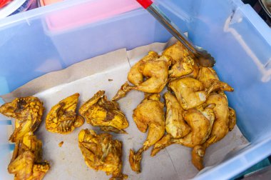 Kızartma makinesi hazır! Salamura edilmiş tavuk parçalarını mükemmel bir şekilde baharatlanmış ve lezzetli bir yemek için hazırlanmış plastik bir kabın içine koyun..