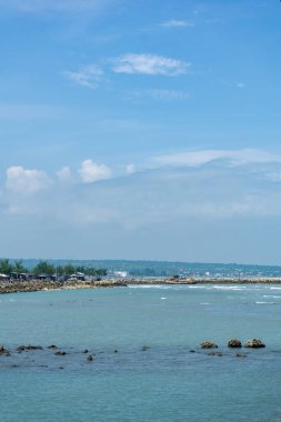 Endonezya, Tuban 'da açık bir gündüz vakti gökyüzü altında çarpıcı kayalık çıkıntıları olan canlı mavi okyanus.