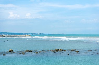 Endonezya, Tuban 'da açık bir gündüz vakti gökyüzü altında çarpıcı kayalık çıkıntıları olan canlı mavi okyanus.