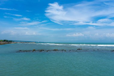Endonezya, Tuban 'da açık bir gündüz vakti gökyüzü altında çarpıcı kayalık çıkıntıları olan canlı mavi okyanus.