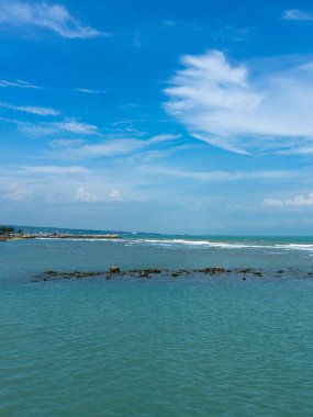 Endonezya, Tuban 'da açık bir gündüz vakti gökyüzü altında çarpıcı kayalık çıkıntıları olan canlı mavi okyanus.