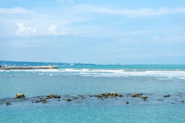 Endonezya, Tuban 'da açık bir gündüz vakti gökyüzü altında çarpıcı kayalık çıkıntıları olan canlı mavi okyanus.