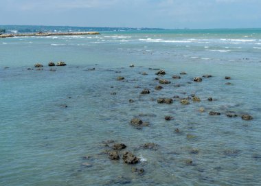 Endonezya, Tuban 'da açık bir gündüz vakti gökyüzü altında çarpıcı kayalık çıkıntıları olan canlı mavi okyanus.