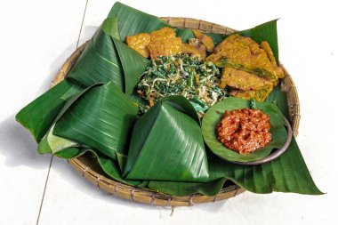 Geleneksel Nasi Pecel yemeği, pilav, sebze ve tempeh, muz yaprakları ve bambu tepsisiyle servis edilir, Endonezya klasiği.